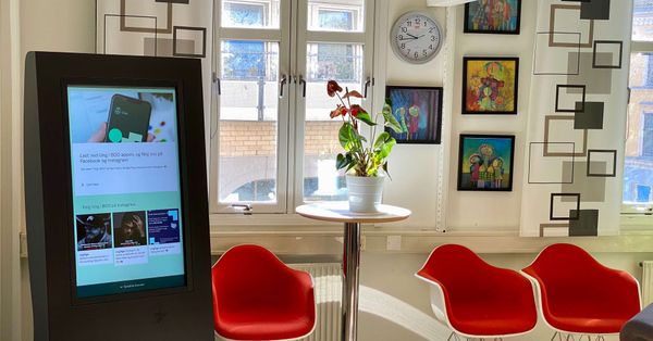 En digital infoskjerm viser informasjon på et venterom. Foto.