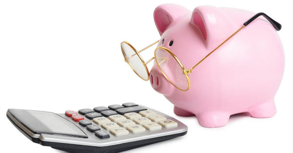 En rosa sparegris med briller ser på en kalkulator.